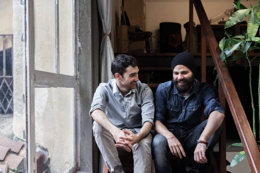 Two young men sitting on a staircase, talking and laughing