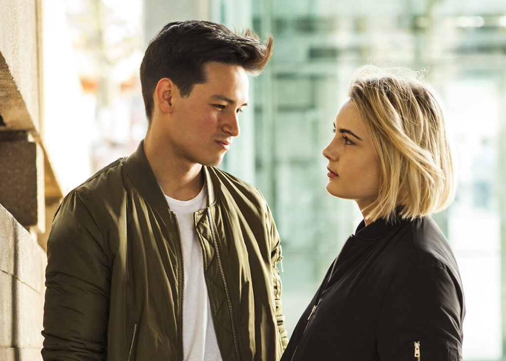 Two people standing face to face outdoors in a serious conversation