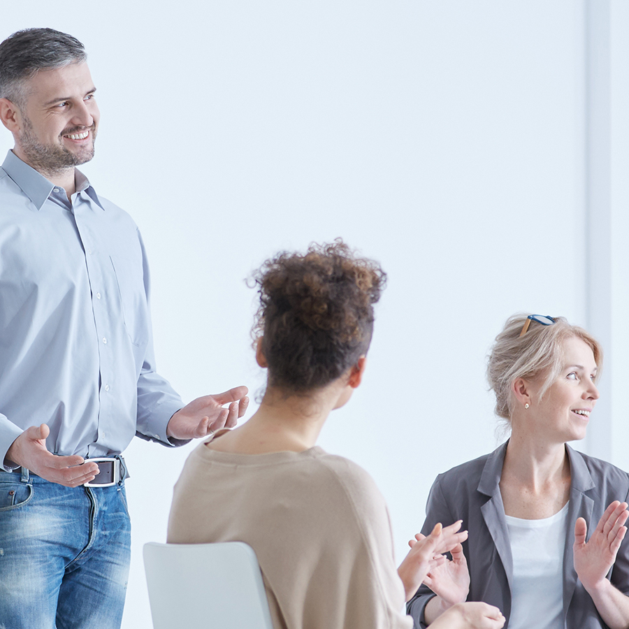 A therapist speaking with a small group of adults during a session