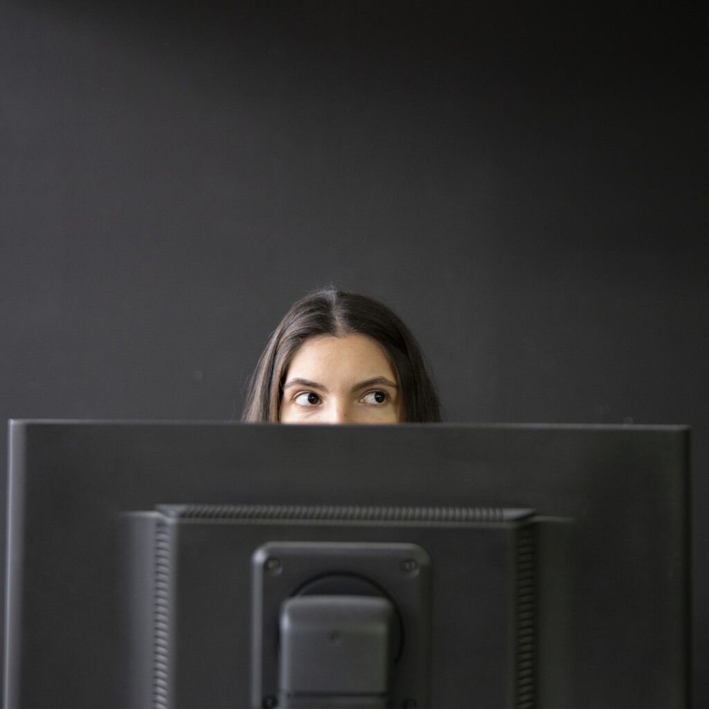 Person looking away from a computer monitor in a darkened room