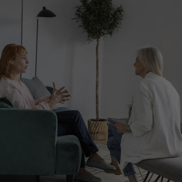 Two women in conversation, one taking notes, representing recovery case management