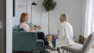 Two women sitting in a bright living room having a relaxed conversation